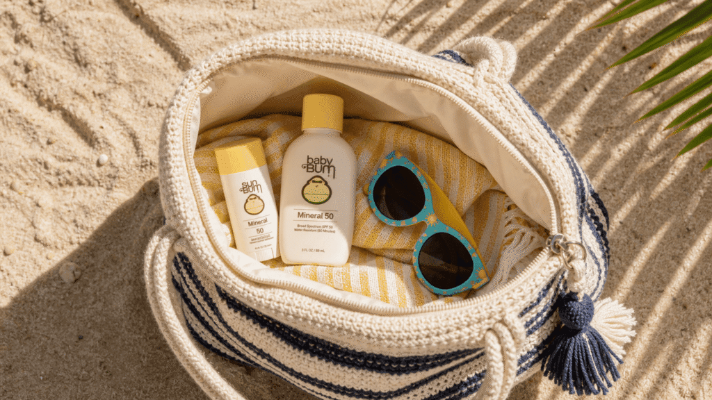 beach bag open on sand showing a sunscreen stick