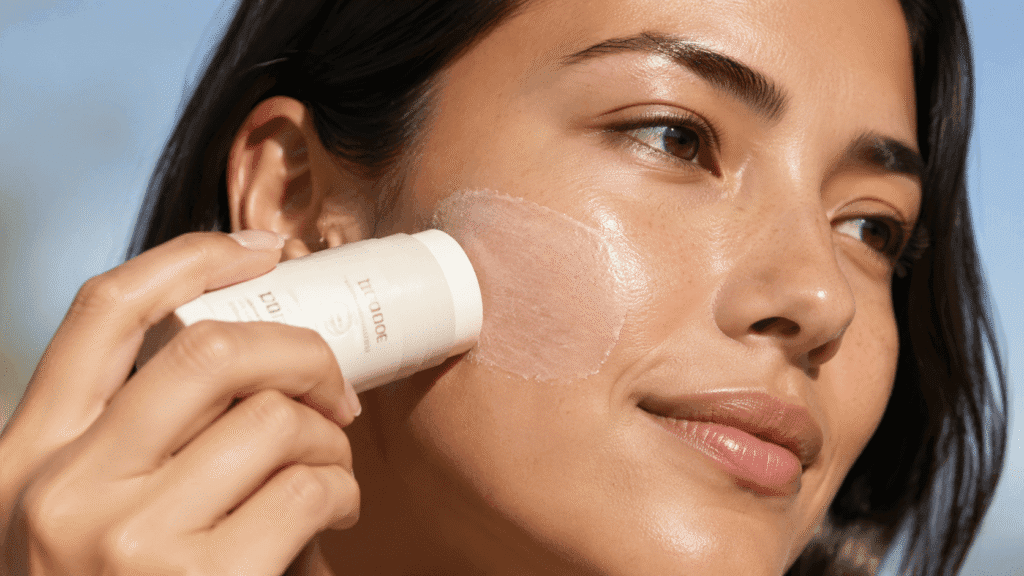 person applying sunscreen stick directly to their face.-2