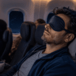 A frustrated traveler on an airplane with wide-open eyes showing inability to sleep