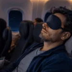 A frustrated traveler on an airplane with wide-open eyes showing inability to sleep