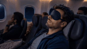 A frustrated traveler on an airplane with wide-open eyes showing inability to sleep