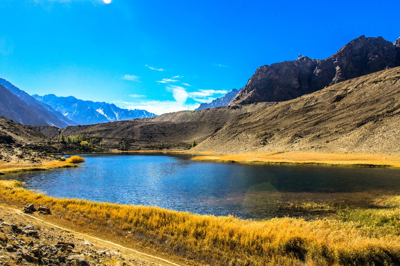 Borith Lake's blue water and golden shore grass beneath the mountains of Gojal.