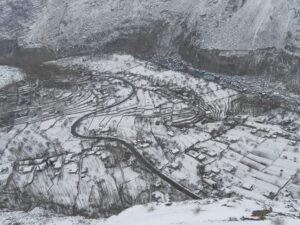 Murtazabad village in Hunza under winter snow, with a road winding through snow-covered fields