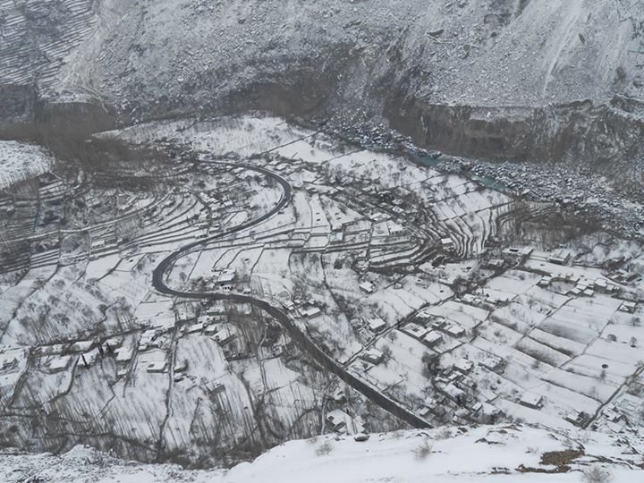 Murtazabad village in Hunza under winter snow, with a road winding through snow-covered fields