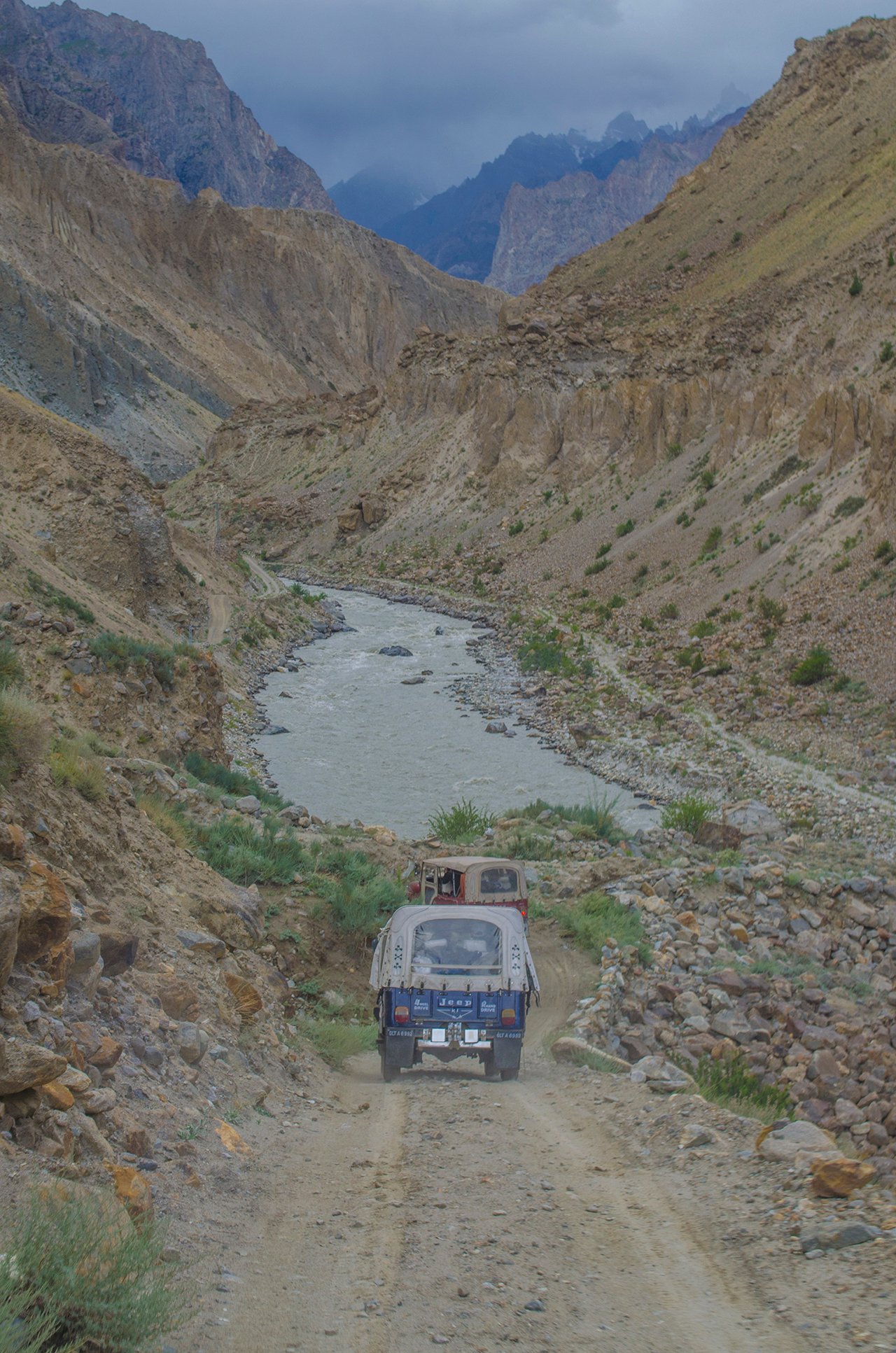 Jeeps driving the dirt road into Hushe Valley beside the river