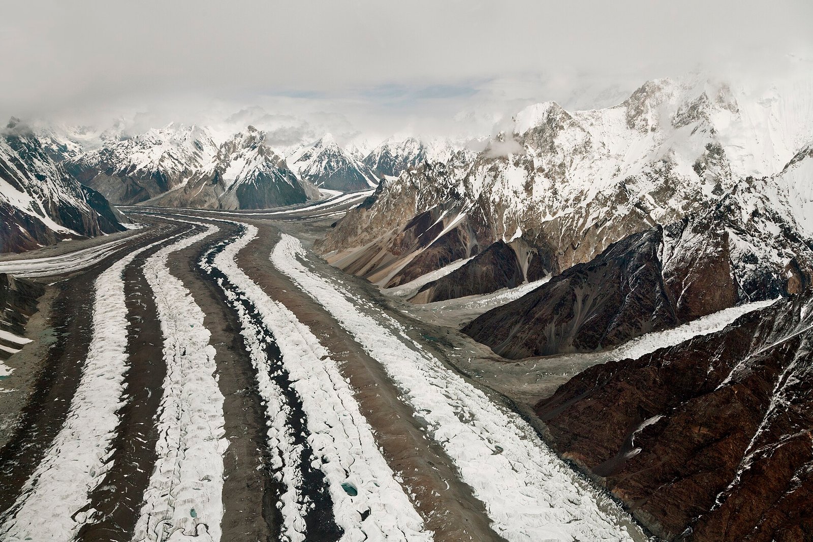 Baltoro Glacier winding between snowy Karakoram peaks, with dark moraine bands across the ice.