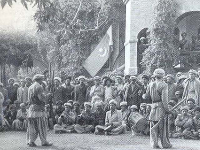 Gilgit Scouts and local men gathered beneath a Pakistani flag in Gilgit, 1947.