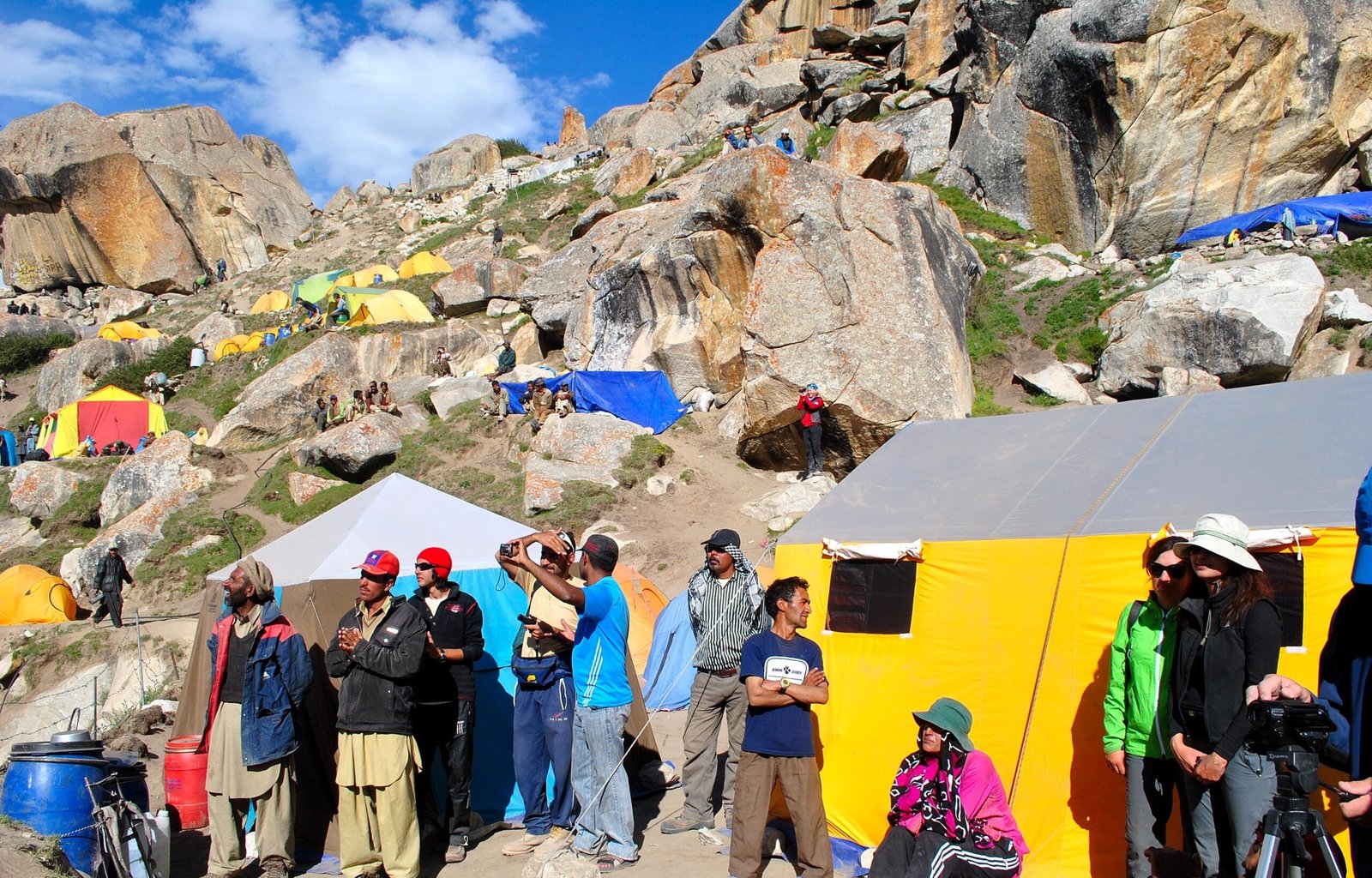 Colourful tents and trekkers at the Urdukas campsite among large boulders on the Baltoro Glacier.