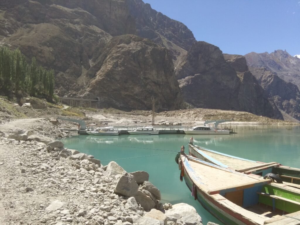 Boats moored at Attabad Lake, with turquoise water and steep bare mountains behind