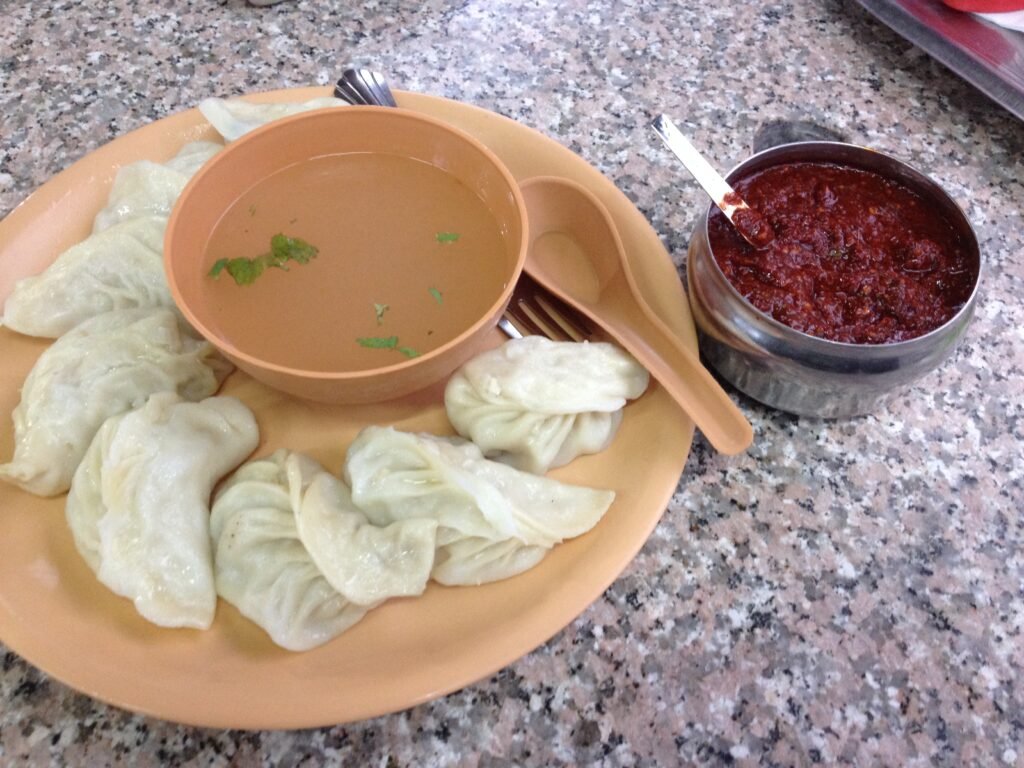 Steamed meat dumplings served with soup and a red chilli dip