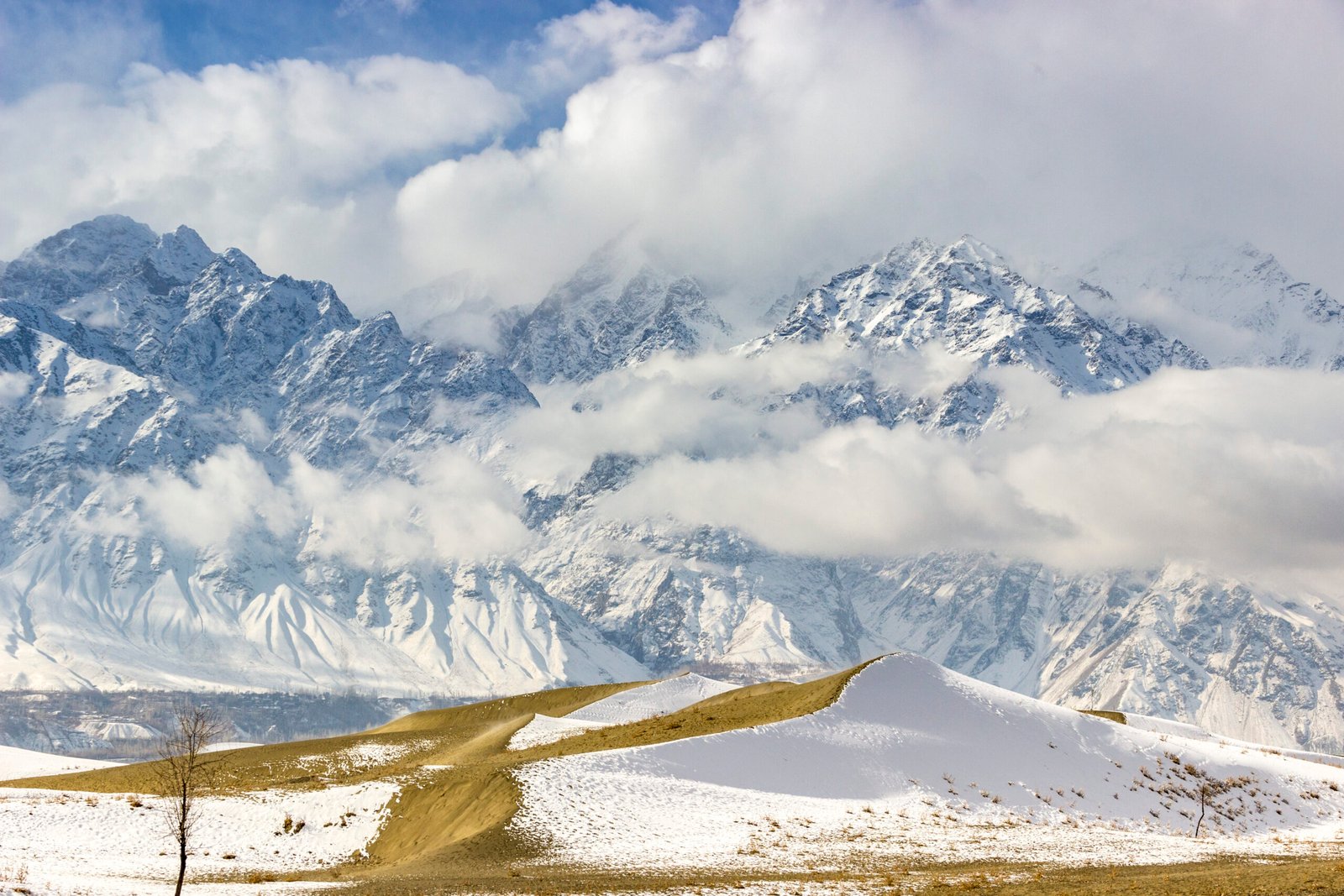 Snow on the Cold Desert dunes near Skardu with snow-covered mountains behind