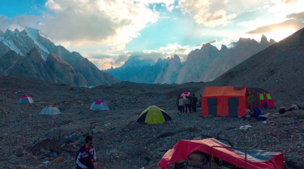 Expedition camp on the Baltoro Glacier moraine at dusk — tents and crew on the K2 base camp trek