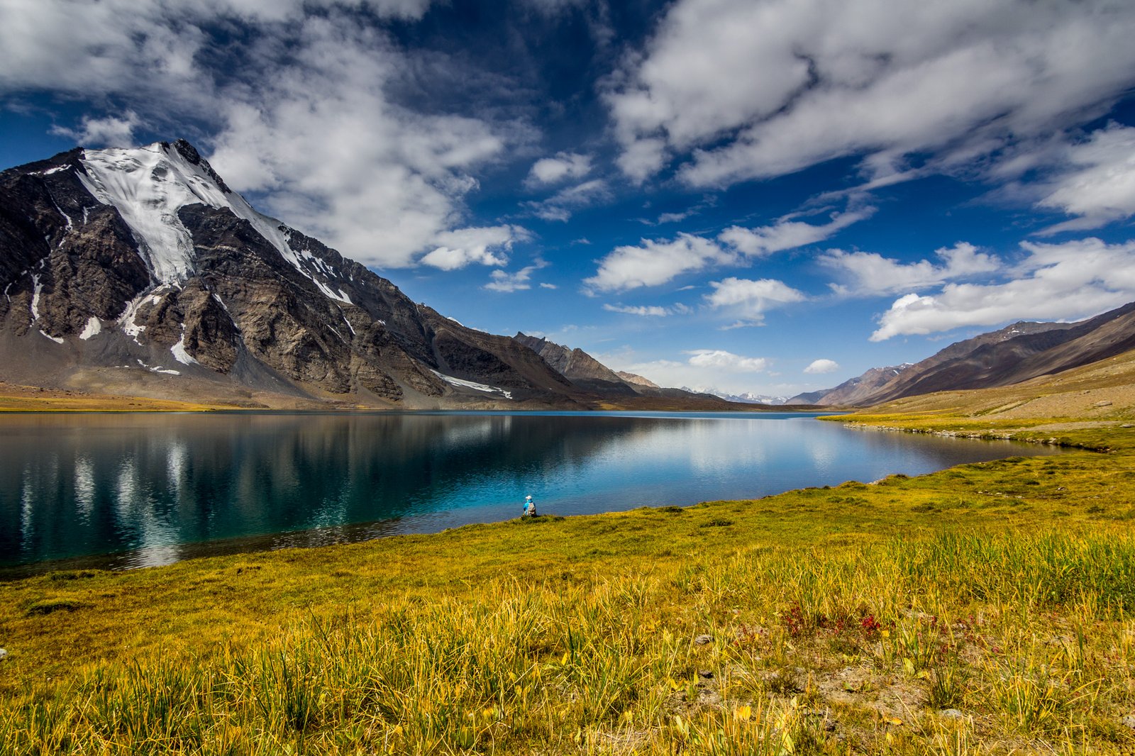 Deep-blue Karambar Lake with snow peaks and golden high pastures in Ishkoman Valley