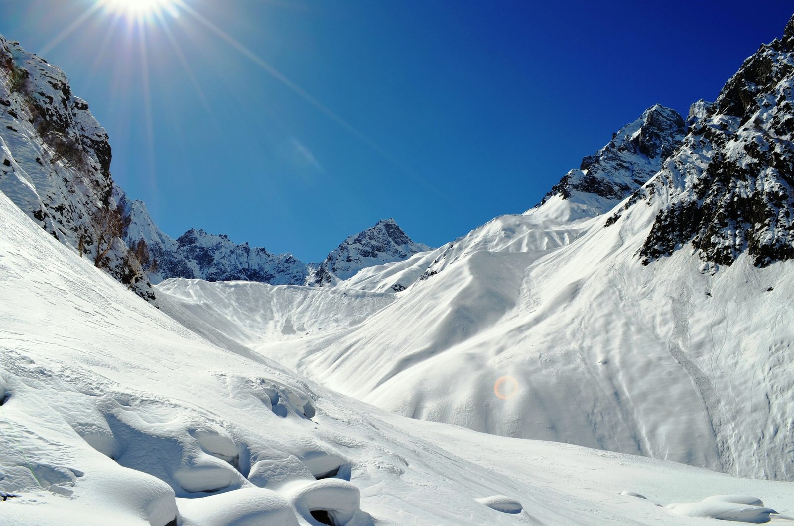 Snow-covered ski slopes under a bright sun at Naltar.