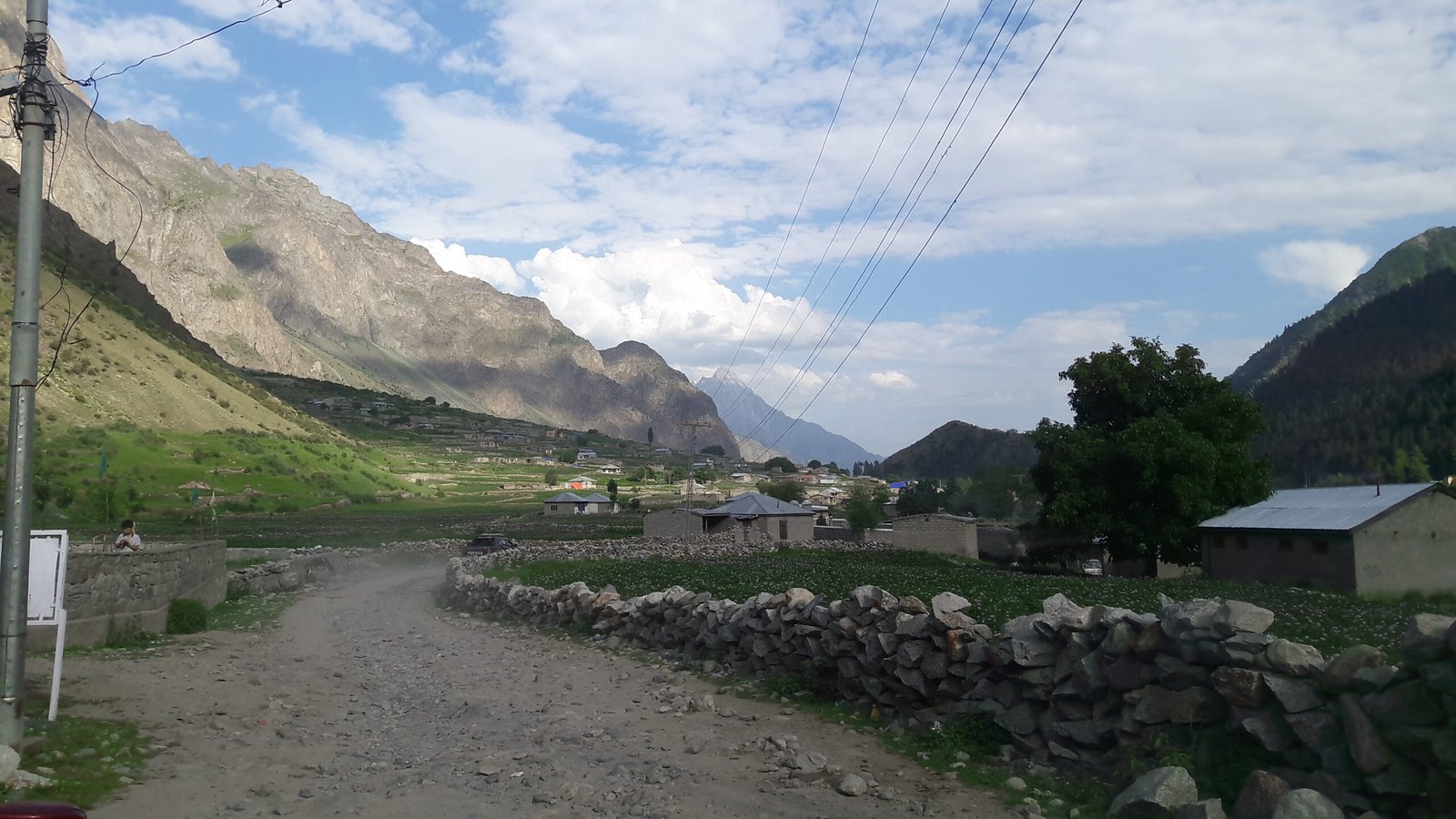 A dirt village road with stone walls and houses in Naltar Valley.