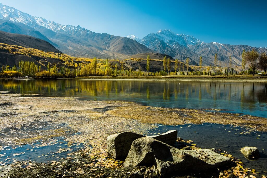 Golden poplars reflected in Phander Lake in Ghizer during peak autumn in Gilgit-Baltistan