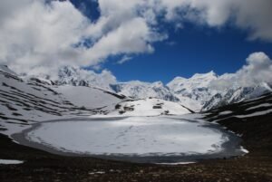 Frozen Rush Lake in a high basin beneath snow peaks